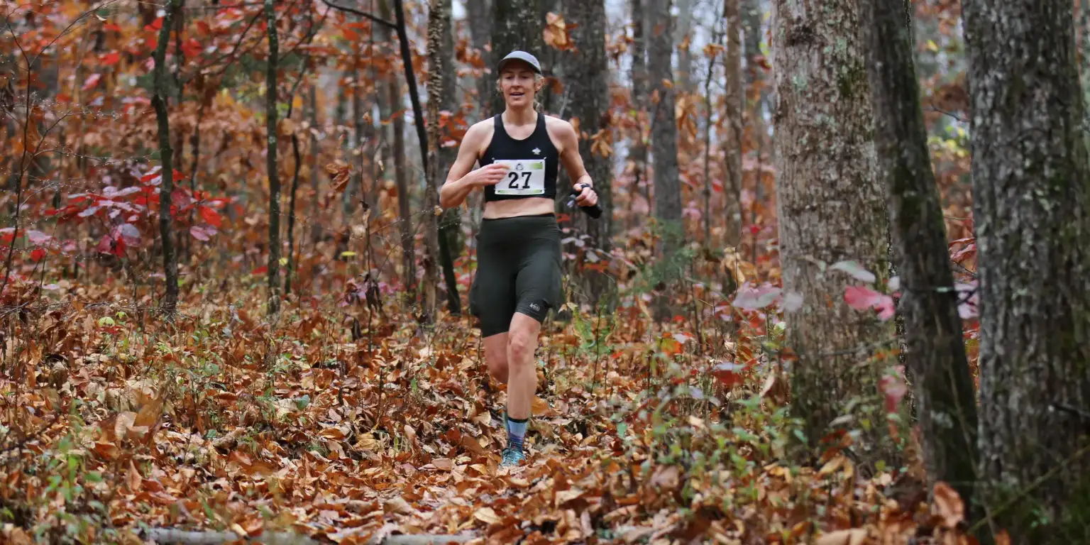 Trail runner on a leaf covered forest path in autumn